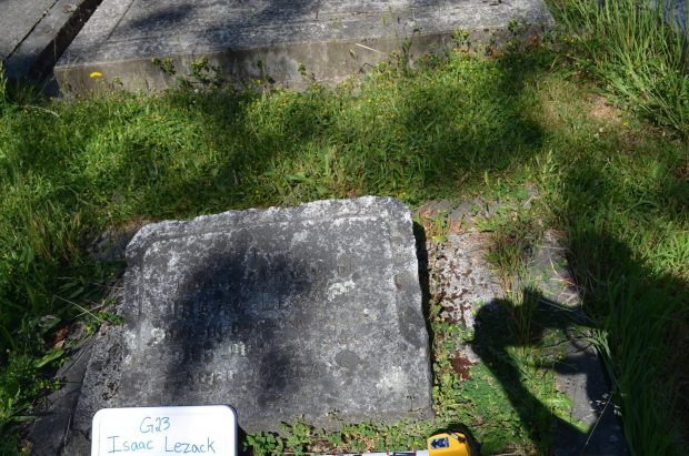 An off-centre photo of a gravestone, with shadows in the middle of the stone, whiteboard and scale bar partially obscured, and strong shadow cast by student.