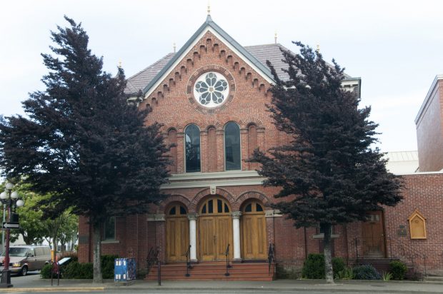 The Emanu-El Synagogue, a redbrick building with a steepled roof, flanked by two trees on either side