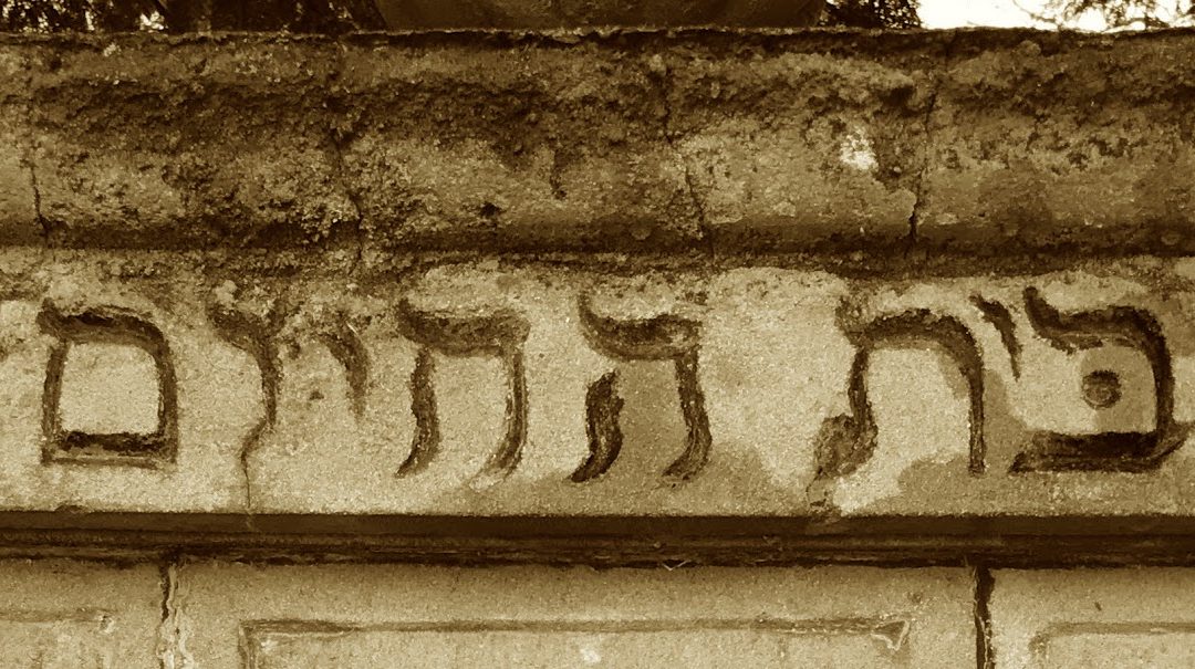 A sepia image of a section of wall at Victoria's Jewish Cemetery. The section of wall contains an inscription in Hebrew.