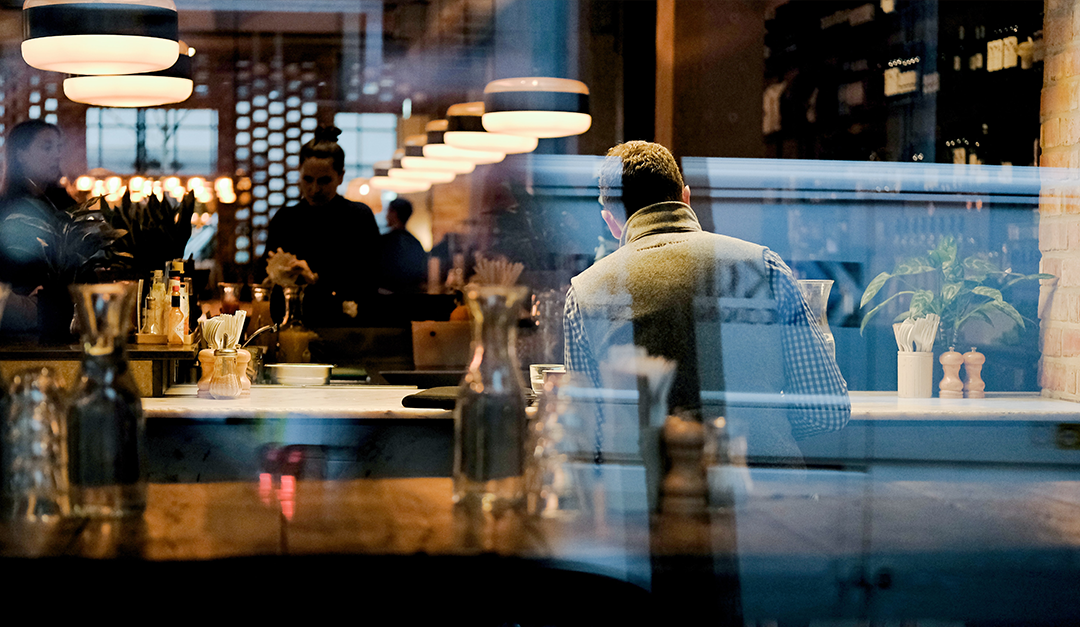 A man sitting at the bar of a restaurant in the evening