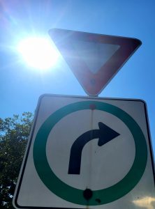 A right turn sign and a yield sign in the sun.