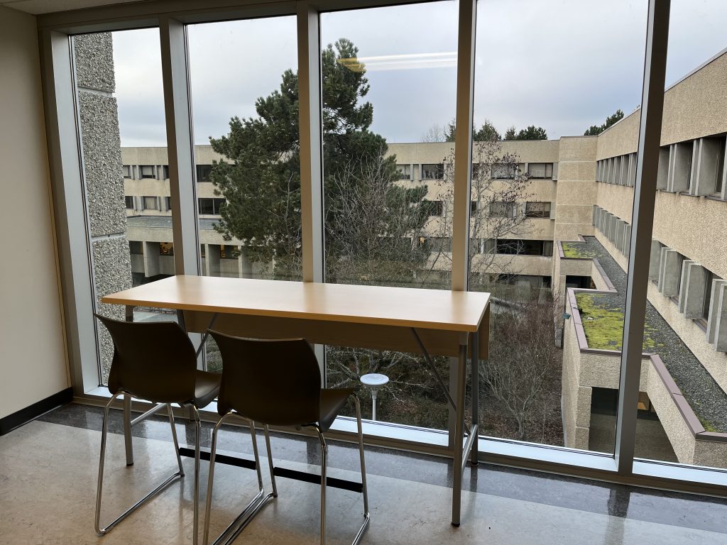 Chairs at a desk in front of a window looking onto campus