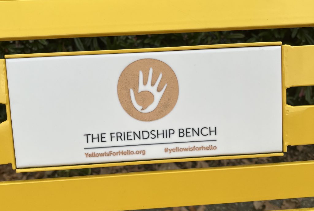 Yellow bench with sign saying "the friendship bench"