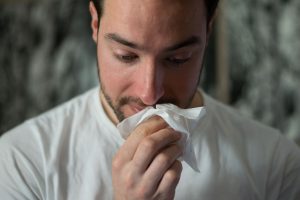 man wiping nose with tissue