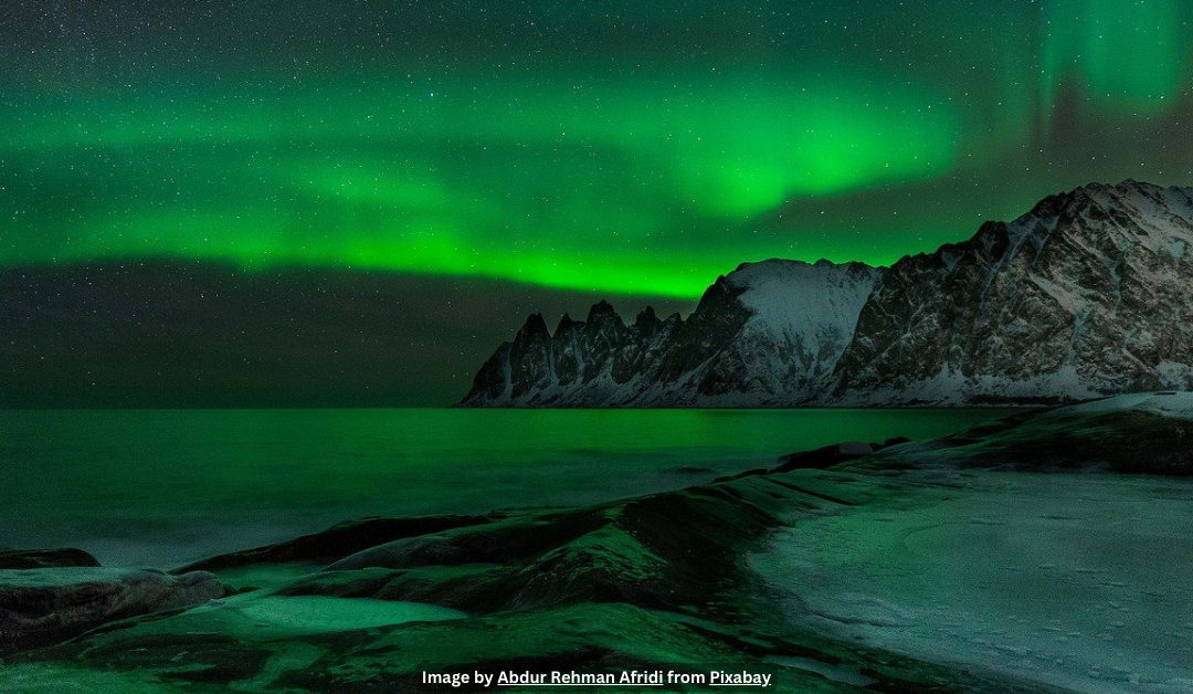 Green northern lights over top of a snowy winter beach.