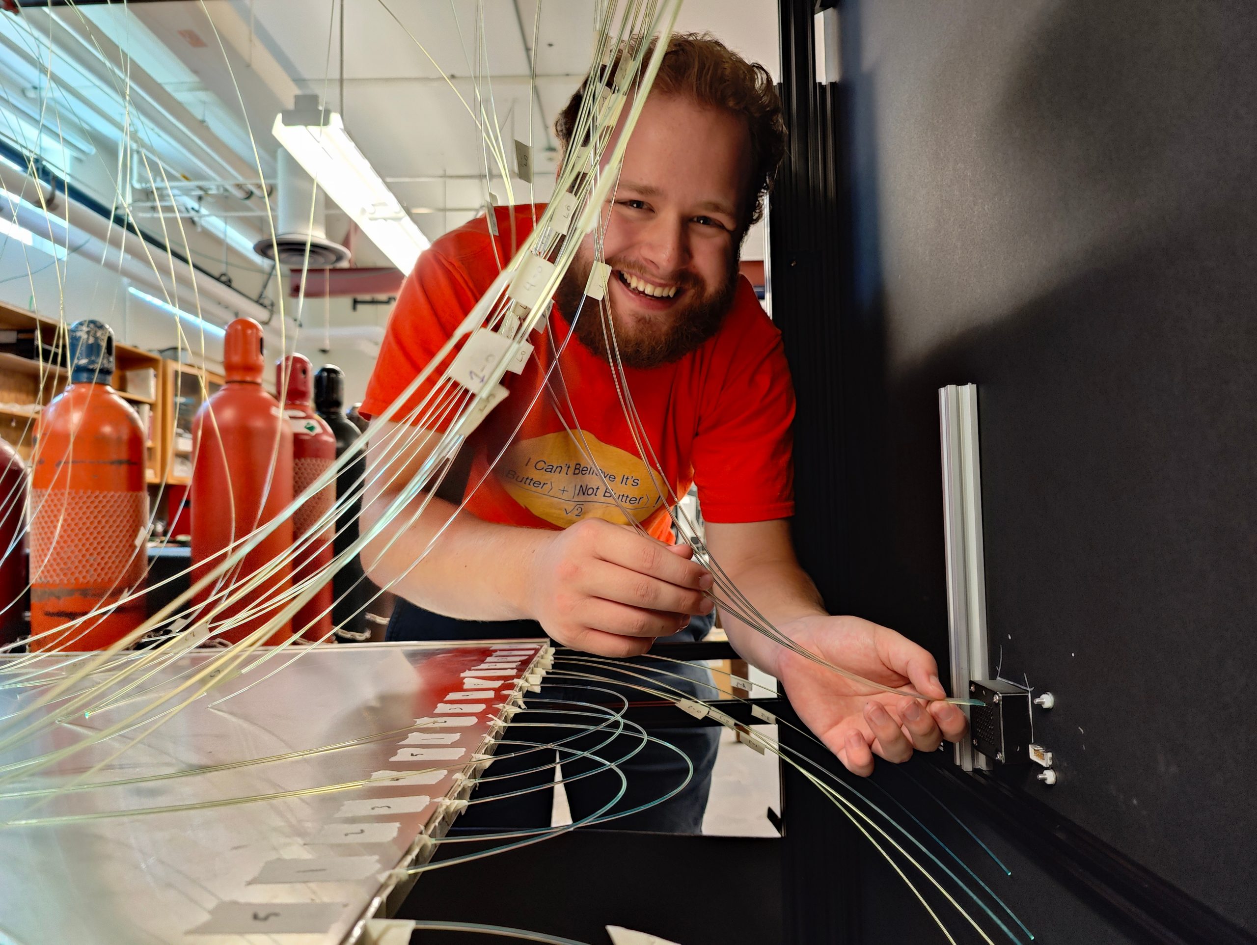 student wearing red shirt splicing fibre optic cable