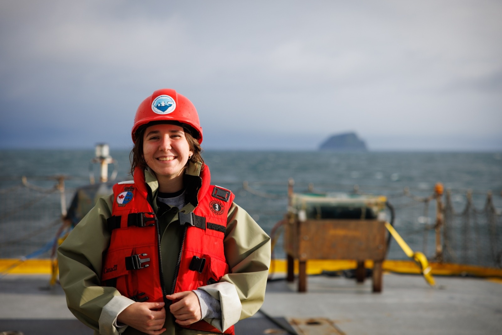 student wearing a life jacket and hard hat on a research vessel