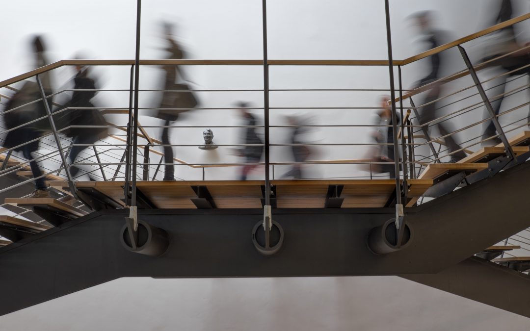 People walking quickly on an upper floor of a college campus