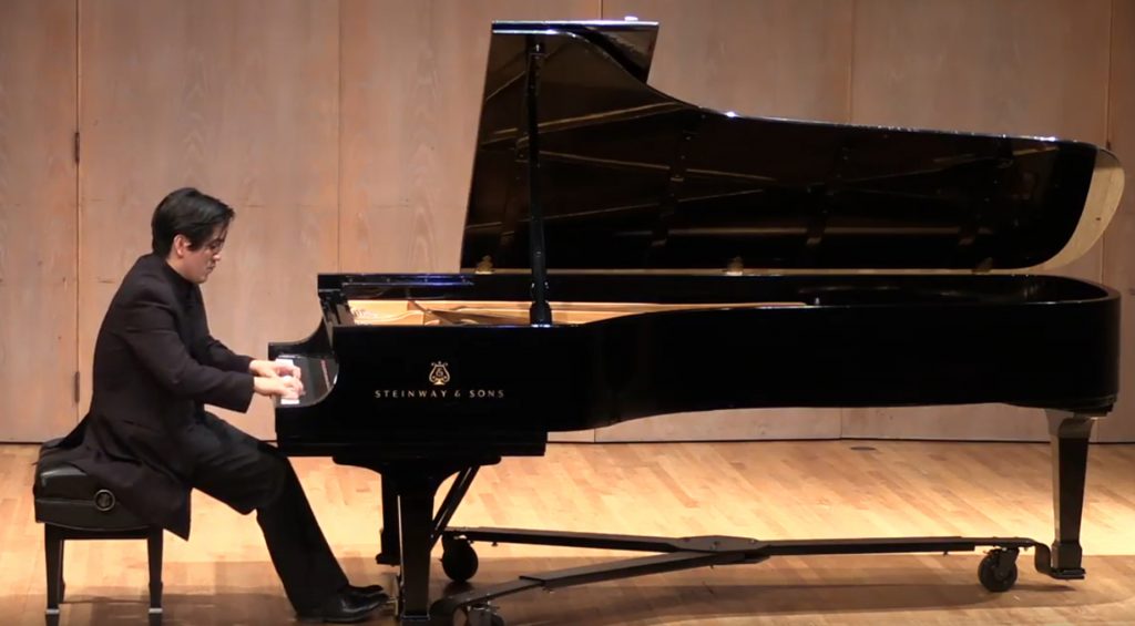Pianist sits at a large piano
