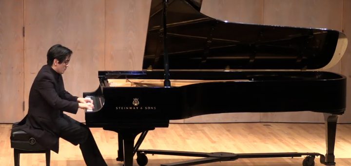 Pianist sits at a large piano