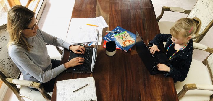 Julie Potter sits at a table facing her daughter. Both are on laptops.