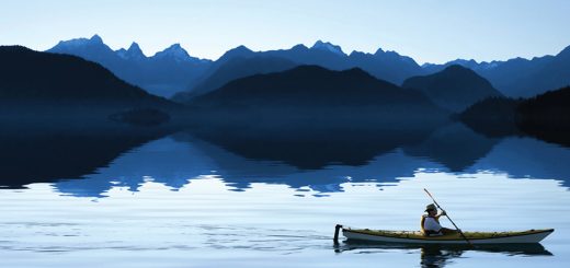 canoe in calm water in front of mountain range