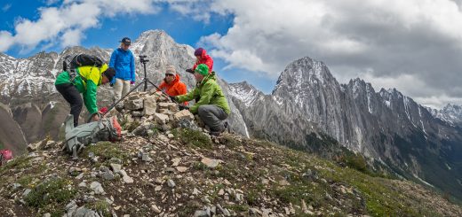 Field crew adjusts photography equipment on a mountain ridge.