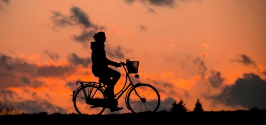 silhouette of a woman on a bike against sunset