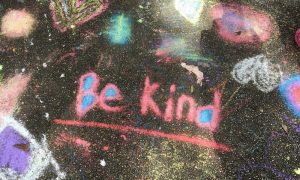 'Be kind' written in chalk on pavement