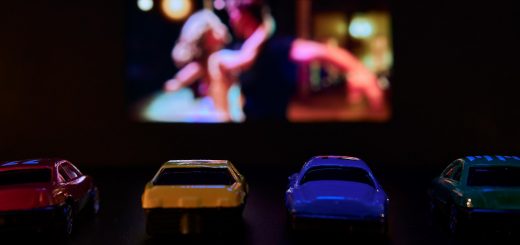 toy cars parked with movie showing in distance