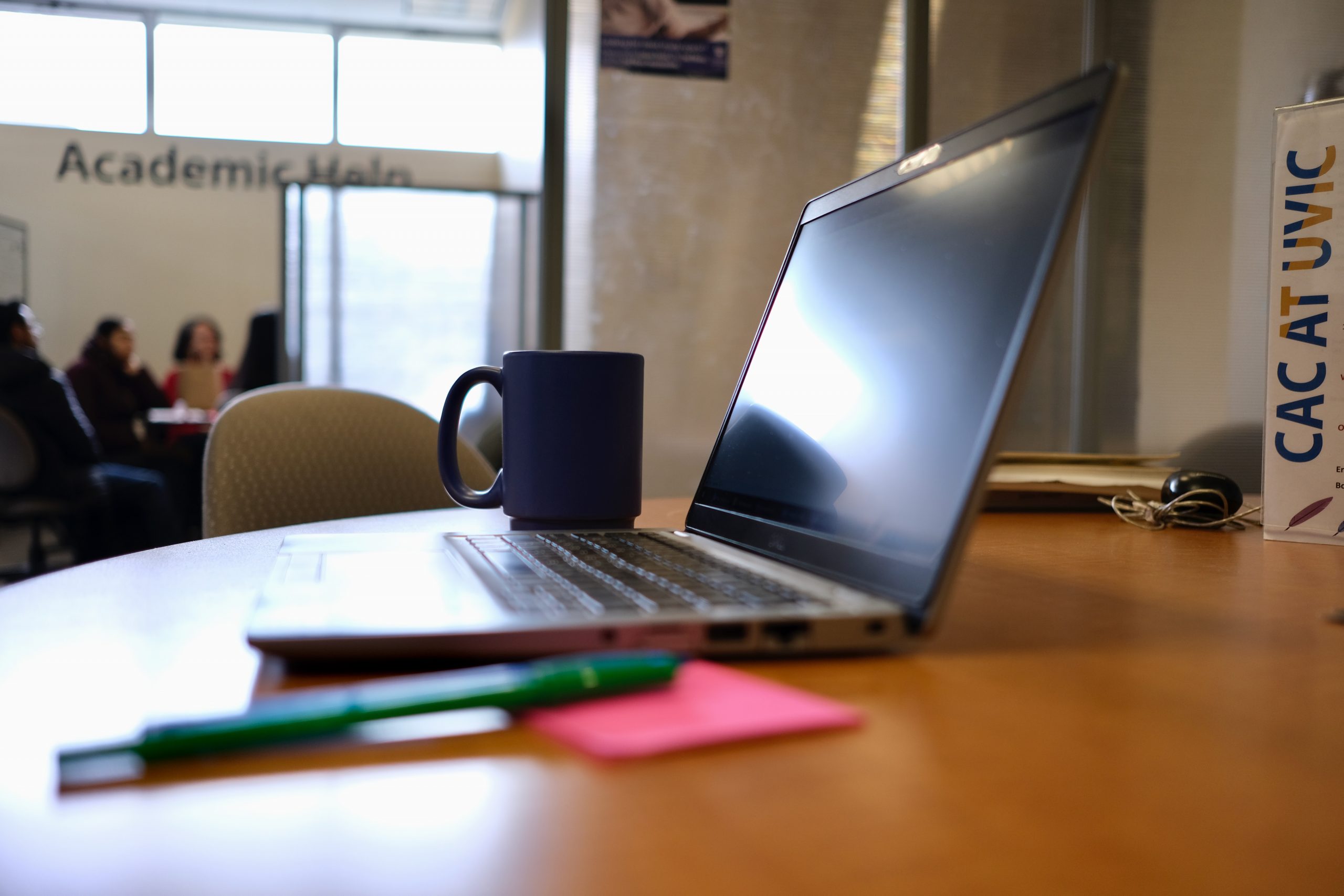 Computer on desk with mug pens and some sticky notes